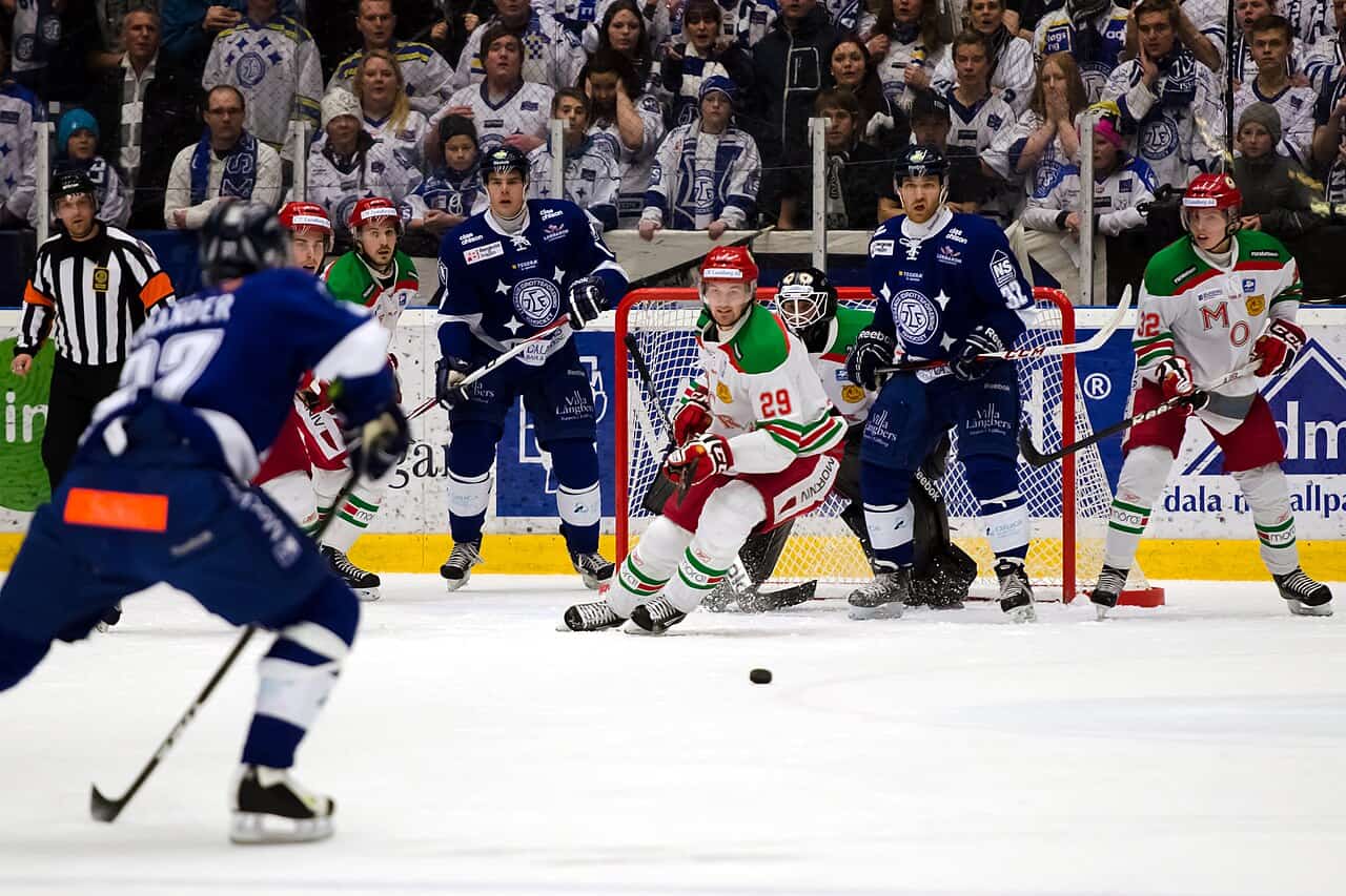 Ishockeymatch där en spelare skjuter mot mål inför publiken